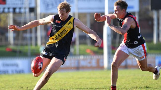 Glenelg’s Joshua Scott gets a kick away ahead of West Adelaide’s Errin Wasley-Black. Picture: AAP/ Keryn Stevens