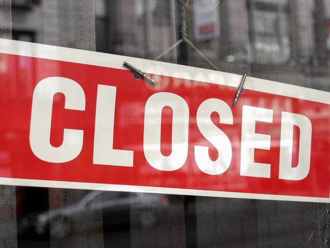 Closed sign in a shop showroom with reflections - red sign over desaturated background