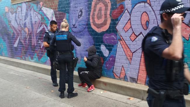 Police officers stop a man for consuming alcohol in public.