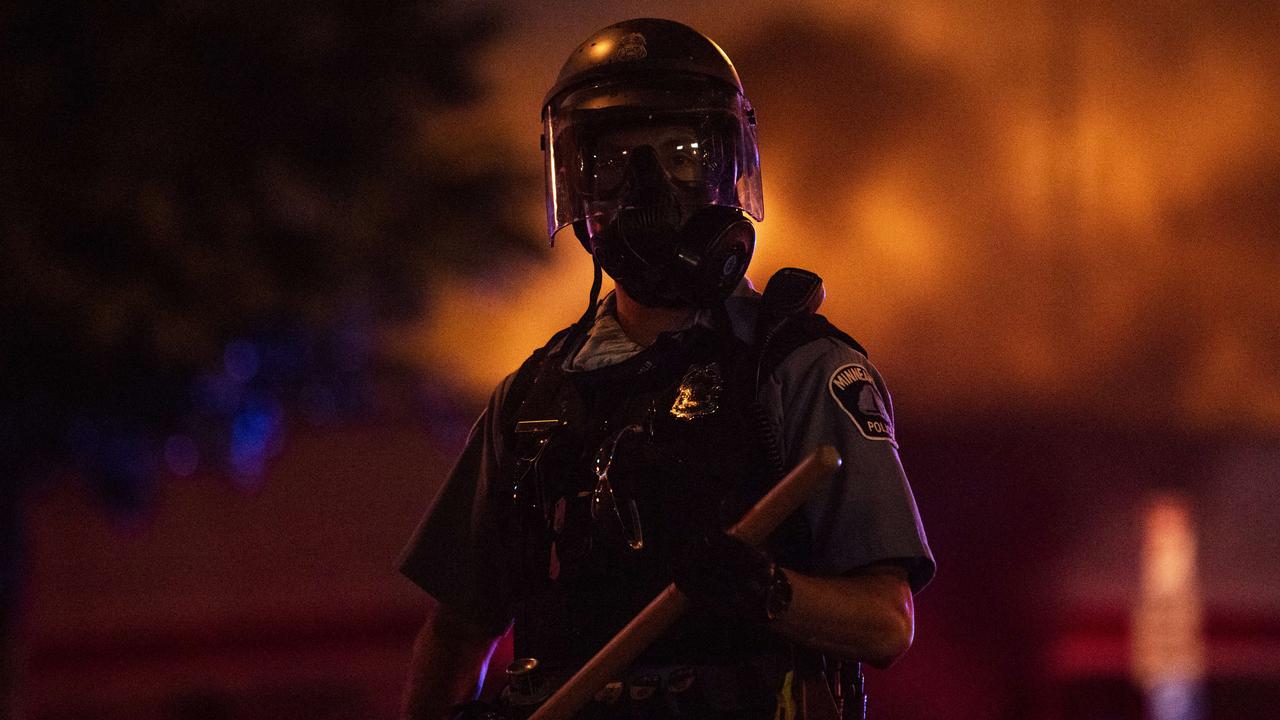 A police officer stands with a baton as a fire burns near the Third Police Precinct in Minneapolis, Minnesota. Businesses have been looted and damaged during ongoing protests following the death of George Floyd. Picture: Getty Images