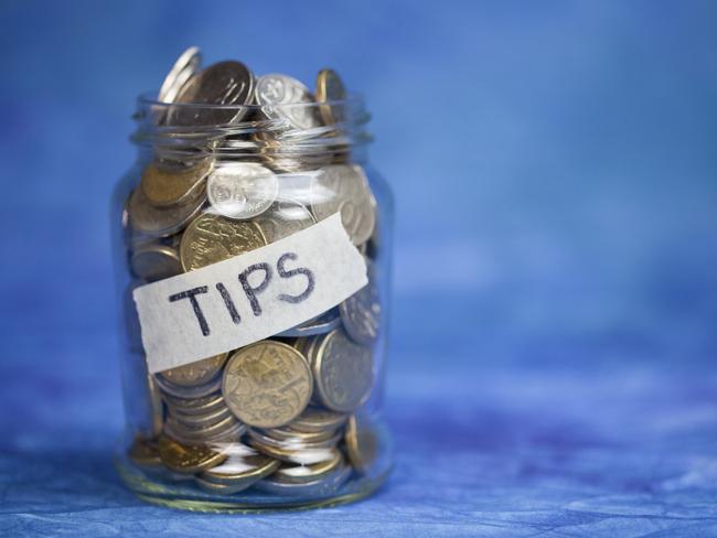 A very full tips jar. Studio shot on a blue background. Australian currency. No people. Money generic.