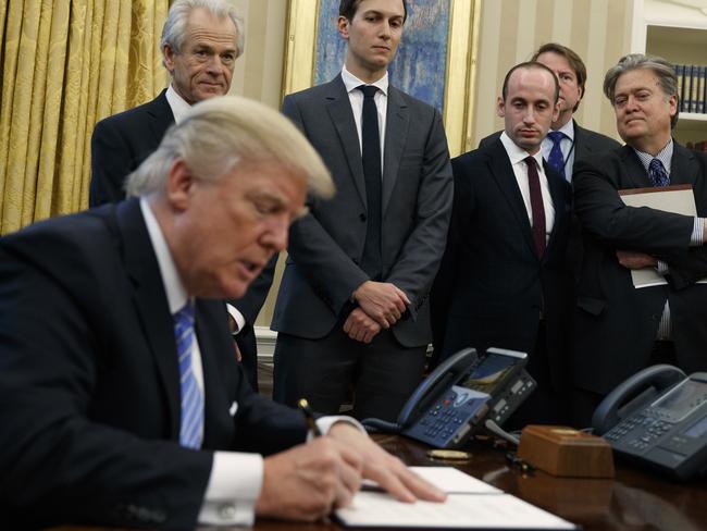 Donald Trump signs executive orders at the White House, flanked by his advisers. Picture: AP Photo/Evan Vucci