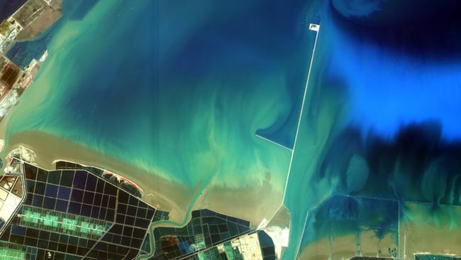 Some farms along a beach. Different shades of blue show different depths of the water.