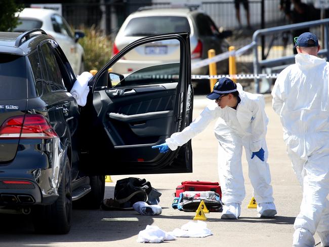 Forensic police gather evidence in and around Hawi’s car where he was shot.