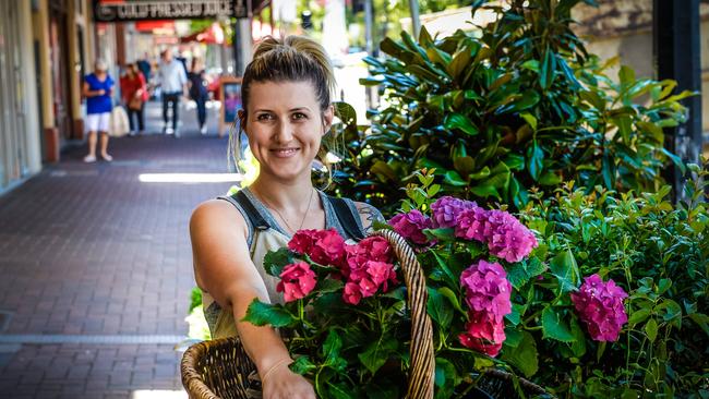 Flower Parade employee Jade Constantinou with some hibiscus plants outside the shop. Picture: AAP/Roy VanDerVegt