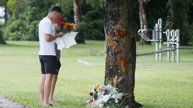 The scene of the fatal traffic crash at Manoora, where the stolen Toyota Yaris left Pease Street near the Saltwater Creek bridge and crashed into a tree. Bradley Smith, 14, died at the scene, and five other children aged 12 to 15 were taken to Cairns Hospital with injuries. A man and a boy lay floral tributes at the scene of the crash. Picture: Brendan Radke