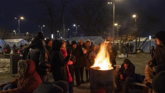 People keep warm by fires outside the main rail terminal in Lviv, Ukraine.