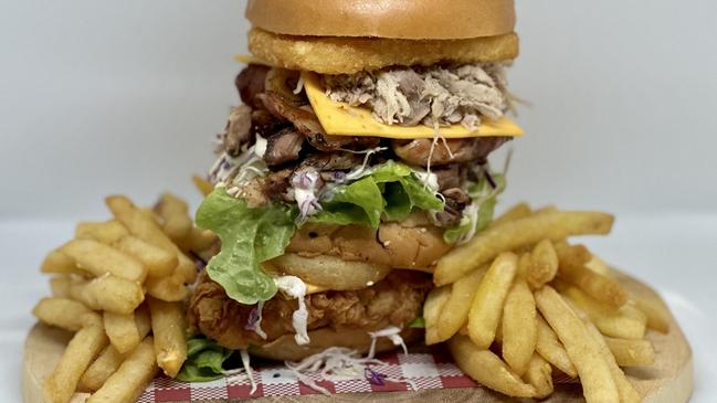 The Mega Boom Burger has chicken, double pulled pork, double beef brisket, crispy bacon, cheese, lettuce, onion rings, slaw, barbecue sauce, mayonnaise and topped with onion rings and a chicken ring.