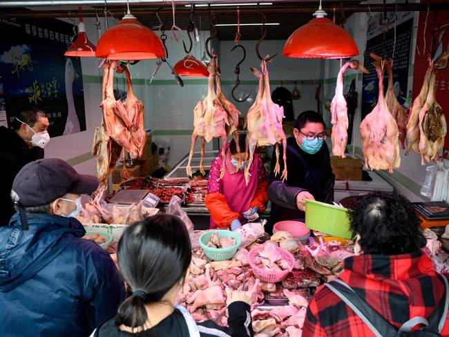 People wearing protective face masks shop at a chicken stall at a wet market in Shanghai on February 13, 2020. - China's official death toll and infection numbers from the deadly COVID-19 coronavirus spiked dramatically on February 13 after authorities changed their counting methods, fuelling concern the epidemic is far worse than being reported. (Photo by NOEL CELIS / AFP)