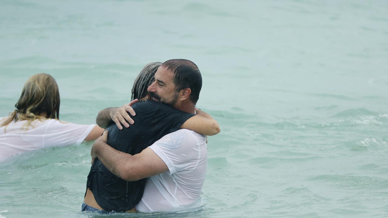 Father Michael Stewart receives a hug in the water at the tribute for his son, Balin Stewart, on his home beach at Buddina. Picture: Lachie Millard