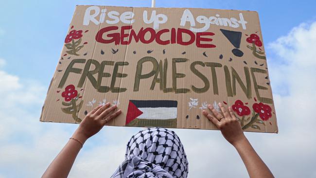 A demonstrator holds a placard reading "Rise up against genocide! Free Palestine" during a Freedom for Palestine rally.