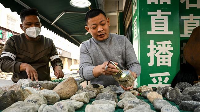 An employee shows a raw jade stone at a shop in Ruili, west Yunnan Province where life is returning to normal. Picture: AFP