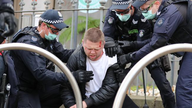 Police restrain a protester at an anti-vaccination rally in Flagstaff Gardens. Picture: Alex Coppel