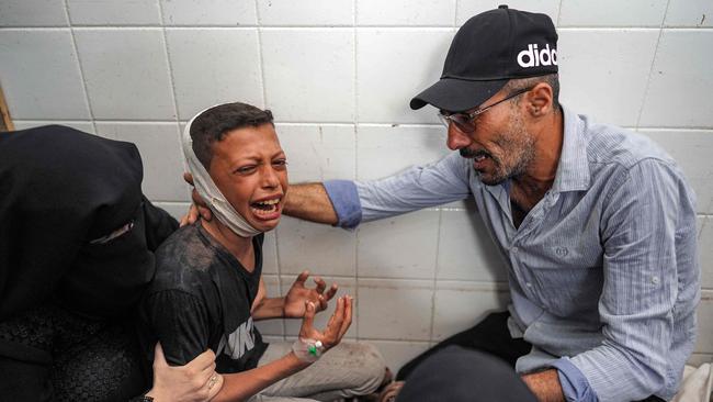 TOPSHOT - A woman and a man comfort an injured boy mourning the loss of his father who was killed in the aftermath of overnight Israeli bombardment in al-Maghazi in the central Gaza Strip, at the morgue of the Aqsa Martyrs hospital in Deir el-Balah on June 25, 2024 amid the ongoing conflict in the Palestinian territory between Israel and Hamas. (Photo by Bashar TALEB / AFP)