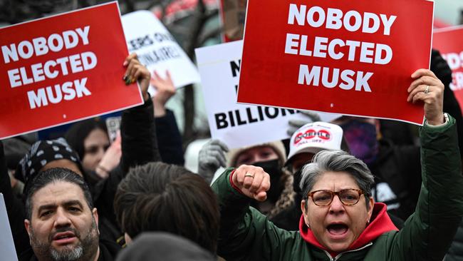 People hold up signs as they protest against Donald Trump and Elon Musk's government workers cuts, near the US Capitol in Washington this week. Picture: AFP