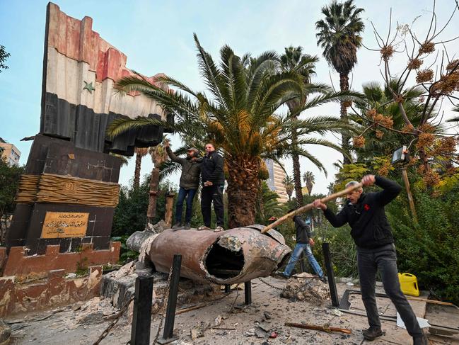 People stand atop a toppled statue of former Syrian president Hafez al-Assad. Picture: AFP