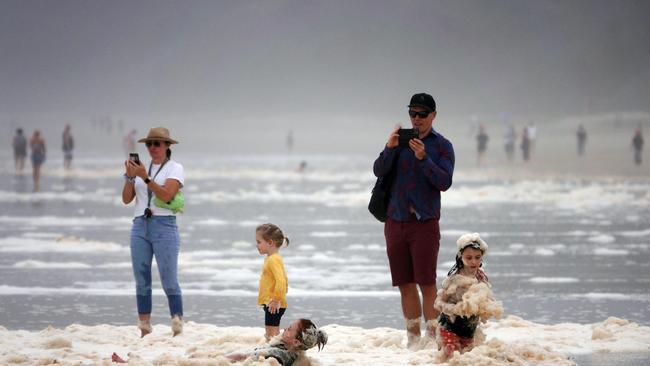 A family playing in sea foam at Burleigh Heads as the wet weather continues in QLD. Picture: Alex Coppel.