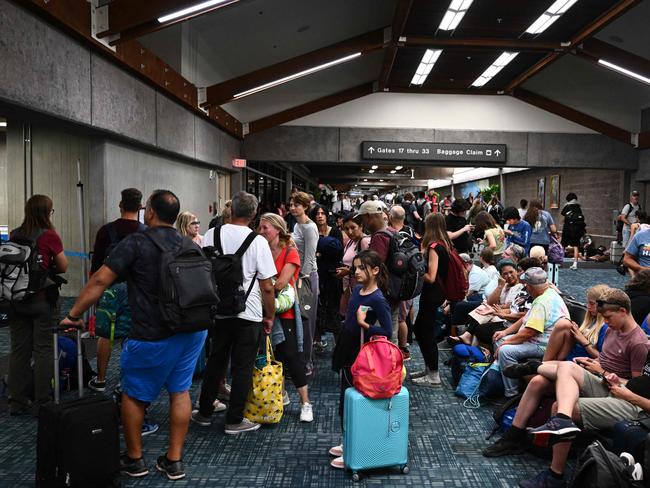 Passengers try to rest and sleep after cancelled and delayed flights while others wait to board flights off the island. Picture: AFP