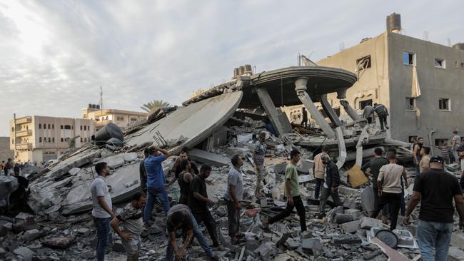 People search through buildings, destroyed during Israeli air strikes in the southern Gaza Strip in Khan Yunis, Gaza.