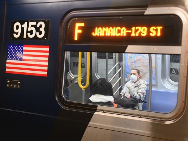 (FILES) In this file photo taken on March 17, 2020, a woman with a face mask rides on the subway in the Brooklyn Borough of New York City. - Public transport was already expected to show its best light in the United States to try to compete with the automobile, but the pandemic has reduced these efforts to nothing, and the sector fears that it will have to lay off again and reduce its supply. Tuesday morning rush hour in the Washington subway. Only four people are seated in the train. Since the pandemic broke in March, traveling standing up is just an old memory. (Photo by Angela Weiss / AFP)