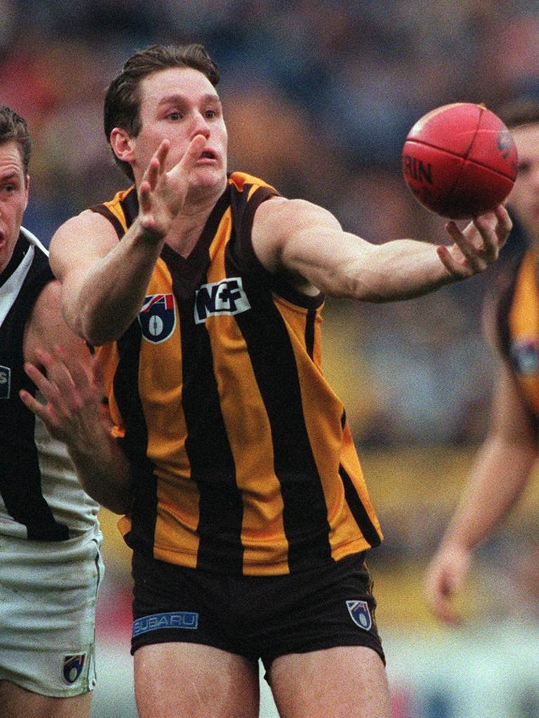 Crawford juggles the ball in front of Paul Williams during a match between the Hawks and Collingwood in 1997.