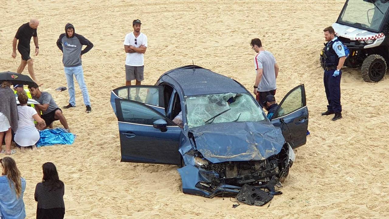 Rescue workers at the scene of a car crash on Maroubra beach, after it plunged 10 metres onto the sand below. Picture: AAP