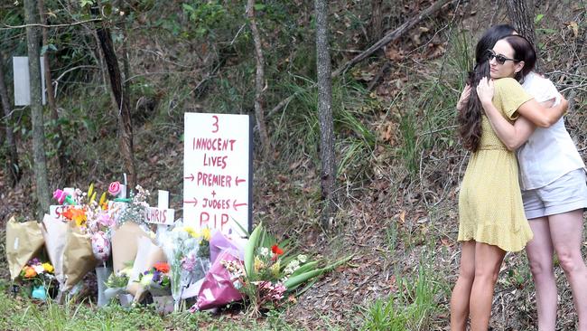 Claudine Snow (right) hugs a resident at the scene where her sister, mother and step-father were killed. Picture: Richard Gosling