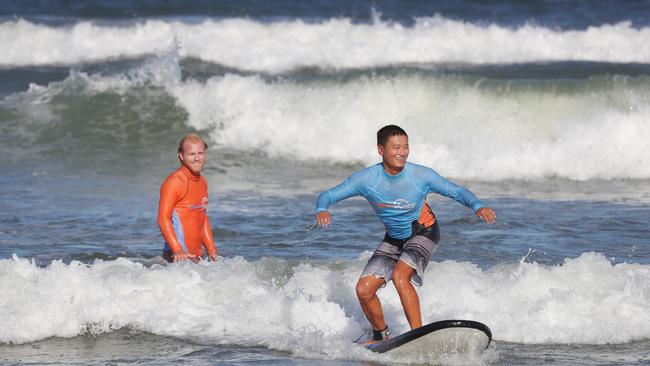 Get Wet Surf School instructor Jack Howlin helps international student Chen Zhang with his surfing skills at The Spit. Picture Glenn Hampson