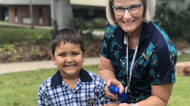 Good Shepherd Catholic School teacher Gail Woodward applies insect repellent to Prep student Zavier Profke after a spike in numbers of mosquitoes after the rain.