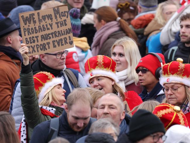 COPENHAGEN, DENMARK - JANUARY 14: Well-wishers wearing crowns hold a sign reading 'We love Mary. Probably the best Australian export ever!' outside Christiansborg Palace on January 14, 2024 in Copenhagen, Denmark. Crown Prince Frederik will succeed Queen Margrethe II, who is stepping down after reigning for 51 years, as King Frederik X later today. (Photo by Sean Gallup/Getty Images)