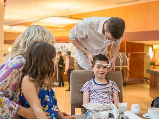 Paddy Duffy is fitted with an EEG headset by Peter Simpson-Young in Singapore, as mum Carlene and sister Stella look on.