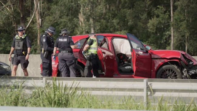 Police officers inspecting a crashed red Porsche on the Bruce Highway. Picture: ABC