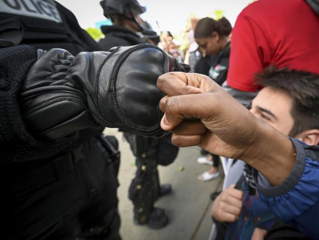 "Respect goes both ways," says a protester named Monique who fist-bumps a Spokane police officer dressed in riot gear outside the Spokane County Courthouse. Picture: AP