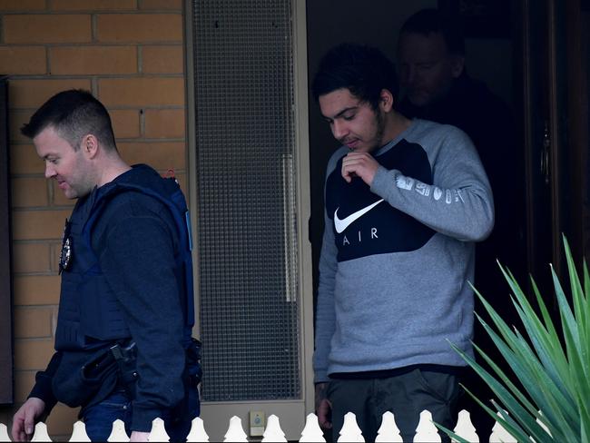 A man comes out of a Gladstone Park house with AFP officers. Picture: Nicole Garmston