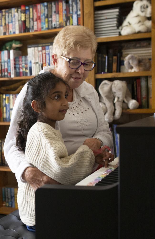 Tharnicaa, 5, learning the piano from Angela Fredericks’ mother Anne Smith, who has come to think of Tharnicaa and Kopika as her own grandchildren. Picture: Russell Shakespeare