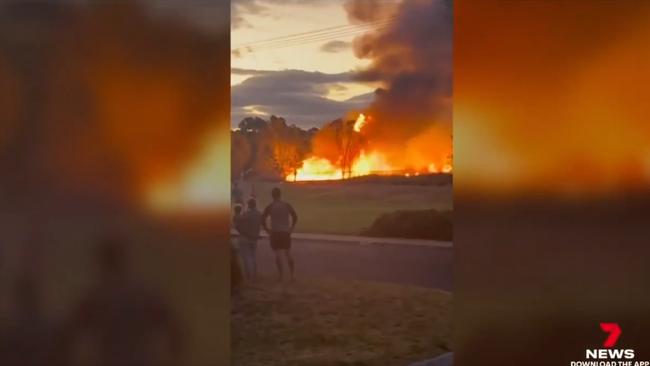 Residents watch on as flames engulf nearby wetlands.