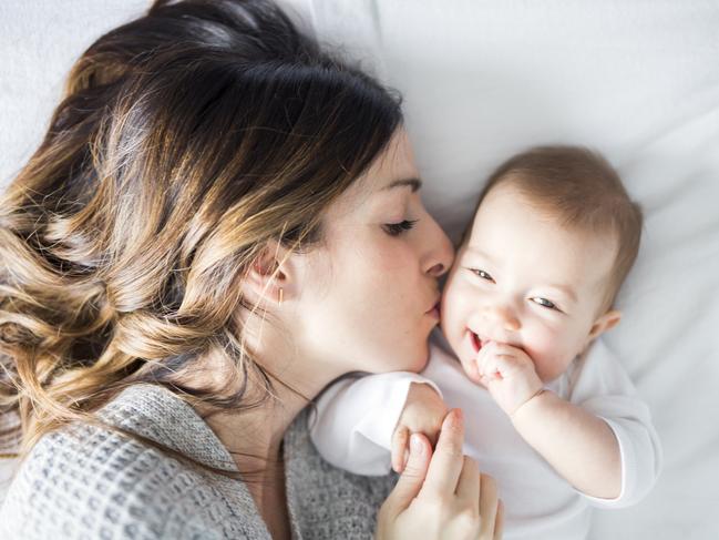 A Mother and baby child on a white bed.