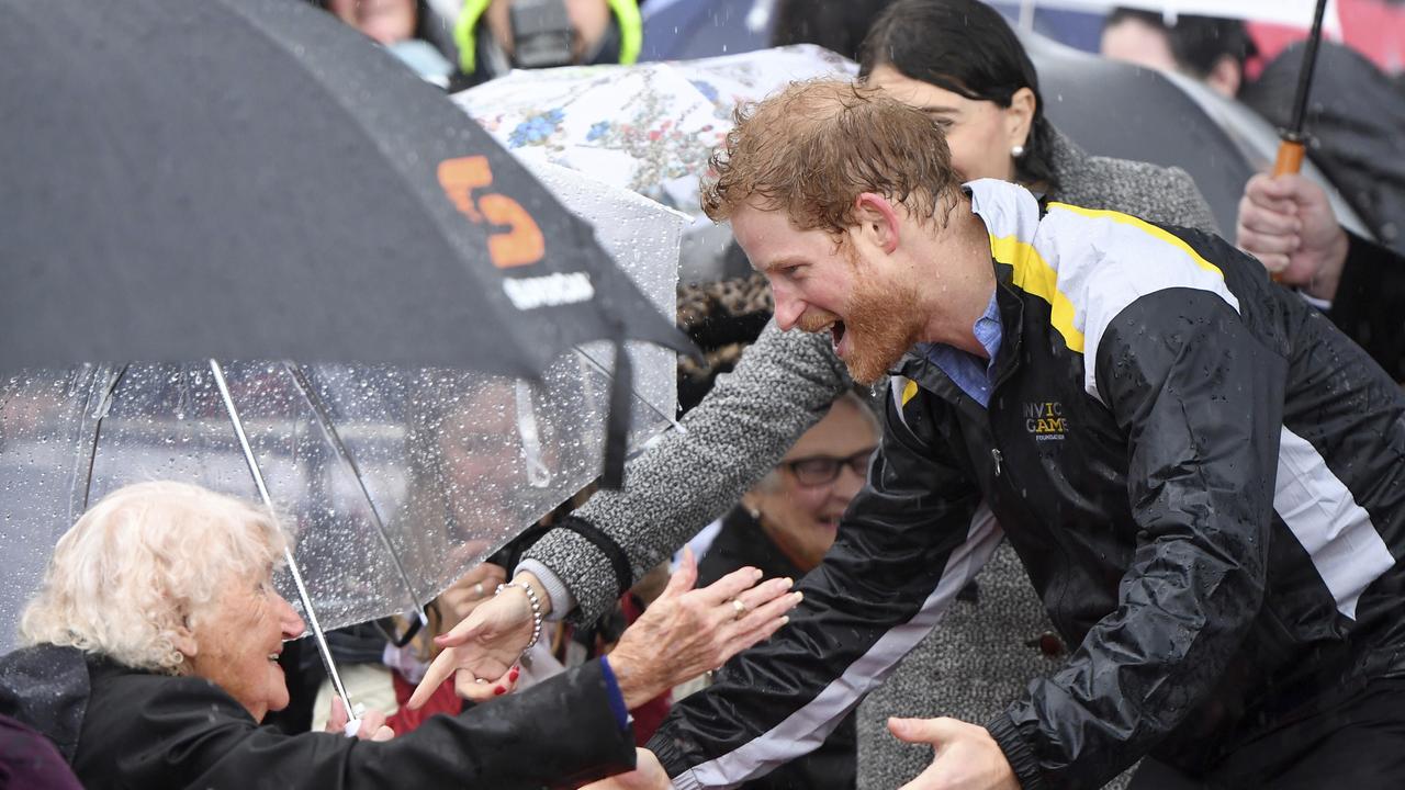 In this June 7, 2017, photo Britain's Prince Harry, right, meets Daphne Dunne, 97, left, during a rainy walk in Sydney. Picture: (Dean Lewins/Pool Photo via AP, File)