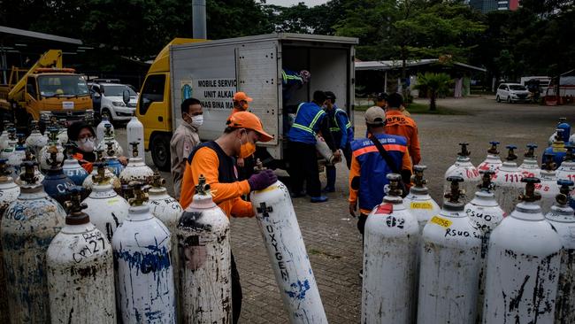 Members of Indonesia's national rescue organizaton offload oxygen tanks to be distributed to hospitals in need in Jakarta. Picture: Getty Images