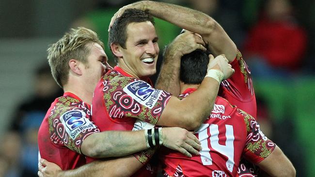 Rod Davies (number 14) is congratulated by Reds teammates after scoring a try against the Rebels.