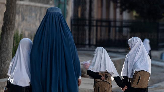 An Afghan woman walks with pupils to their primary school in Kabul on August 9.