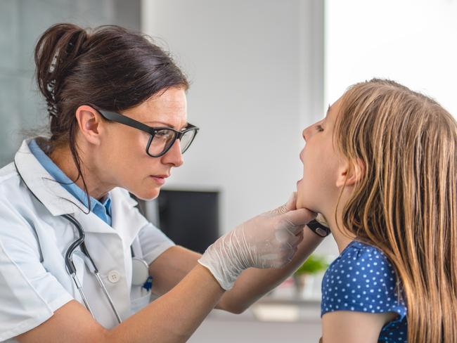 Female doctor checking little girl's throat at medical office