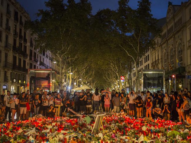 Mourners stand next to candles and flowers in Barcelona. Picture: AP