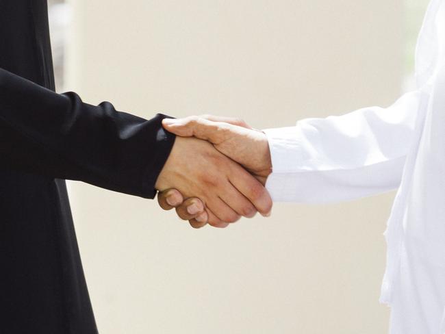 Arab businesswoman shaking hands with middle eastern business colleague