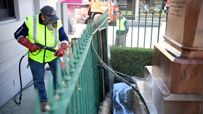 A worker uses a pressure hose to remove graffiti on a Captain Cook statue at Randwick in Sydney on Monday. Picture: Joel Carrett/AAP