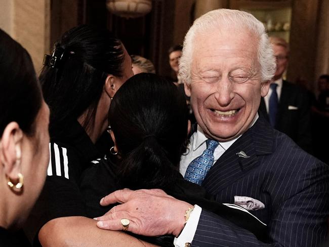 Britain's King Charles III reacts as he is hugged by members of New Zealand's Black Ferns rugby union team, at Buckingham Palace in central London on September 11, 2024. (Photo by Aaron Chown / POOL / AFP)