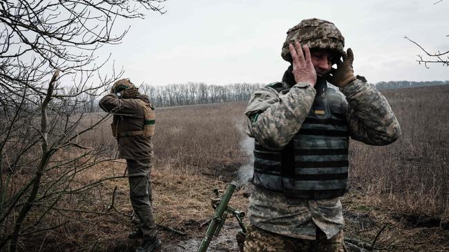 Ukrainian servicemen cover their ears as they fire a 60mm mortar toward Russian positions on the Donetsk front on Tuesday. Picture: AFP