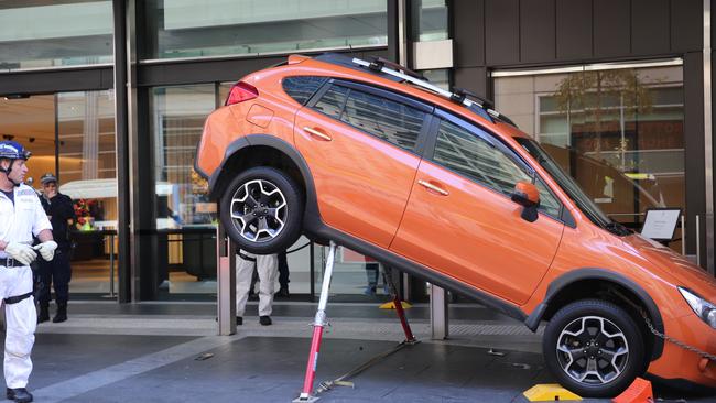 Emergency services carefully lift the Subaru to release the Porsche. Picture: John Grainger