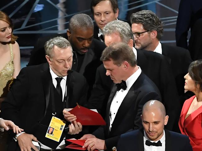 'La La Land' producer Fred Berger speaks at the microphone as production staff and representatives from PricewaterhouseCoopers, Martha L. Ruiz and Brian Cullinan, consult behind him regarding a presentation error of the Best Picture award. Picture: Getty