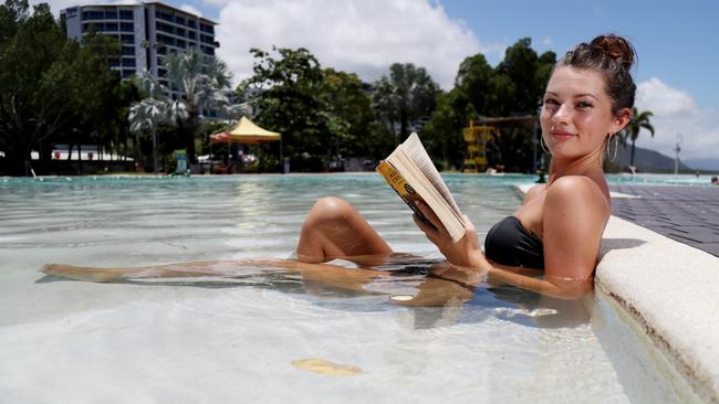 Ella Grieve from Cairns North cools off from the heat while reading a book in the Esplanade lagoon. Picture: Stewart McLean